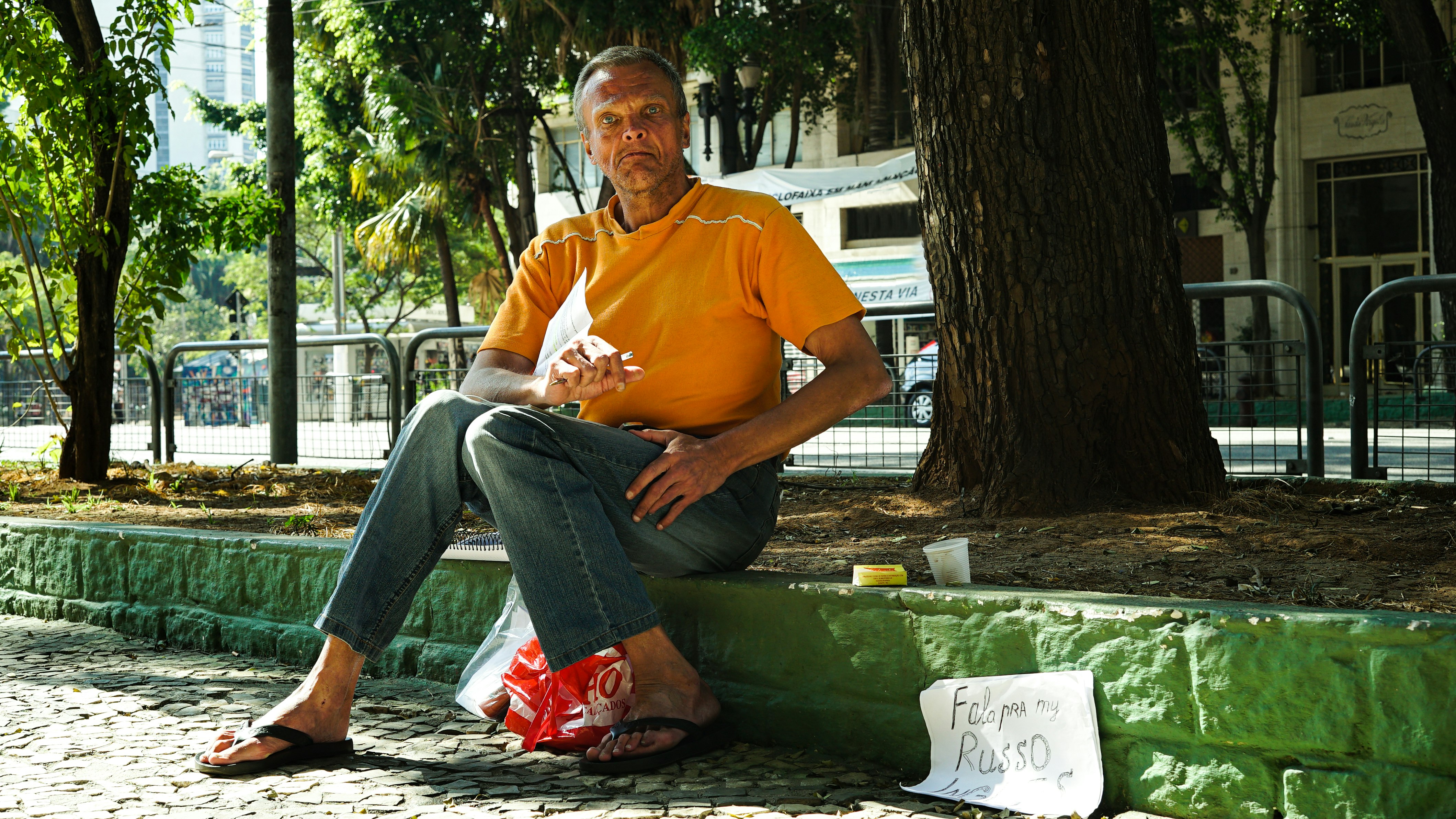 man in yellow polo shirt sitting on green bench